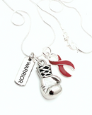 Boxing glove necklace featuring a burgundy dark red ribbon by Rock Your Cause Jewelry, close-up of the jewelry piece.